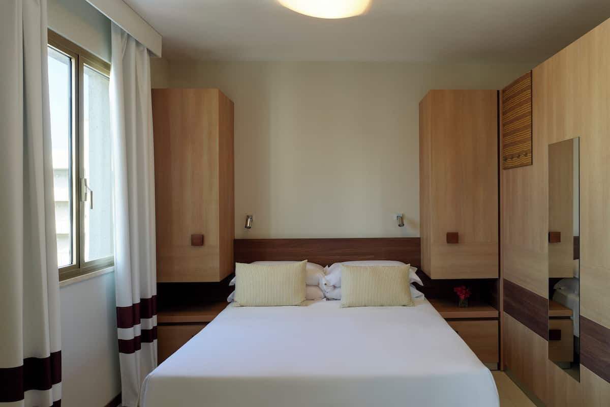 Une chambre d’hôtel avec un grand lit, une armoire en bois et un miroir.