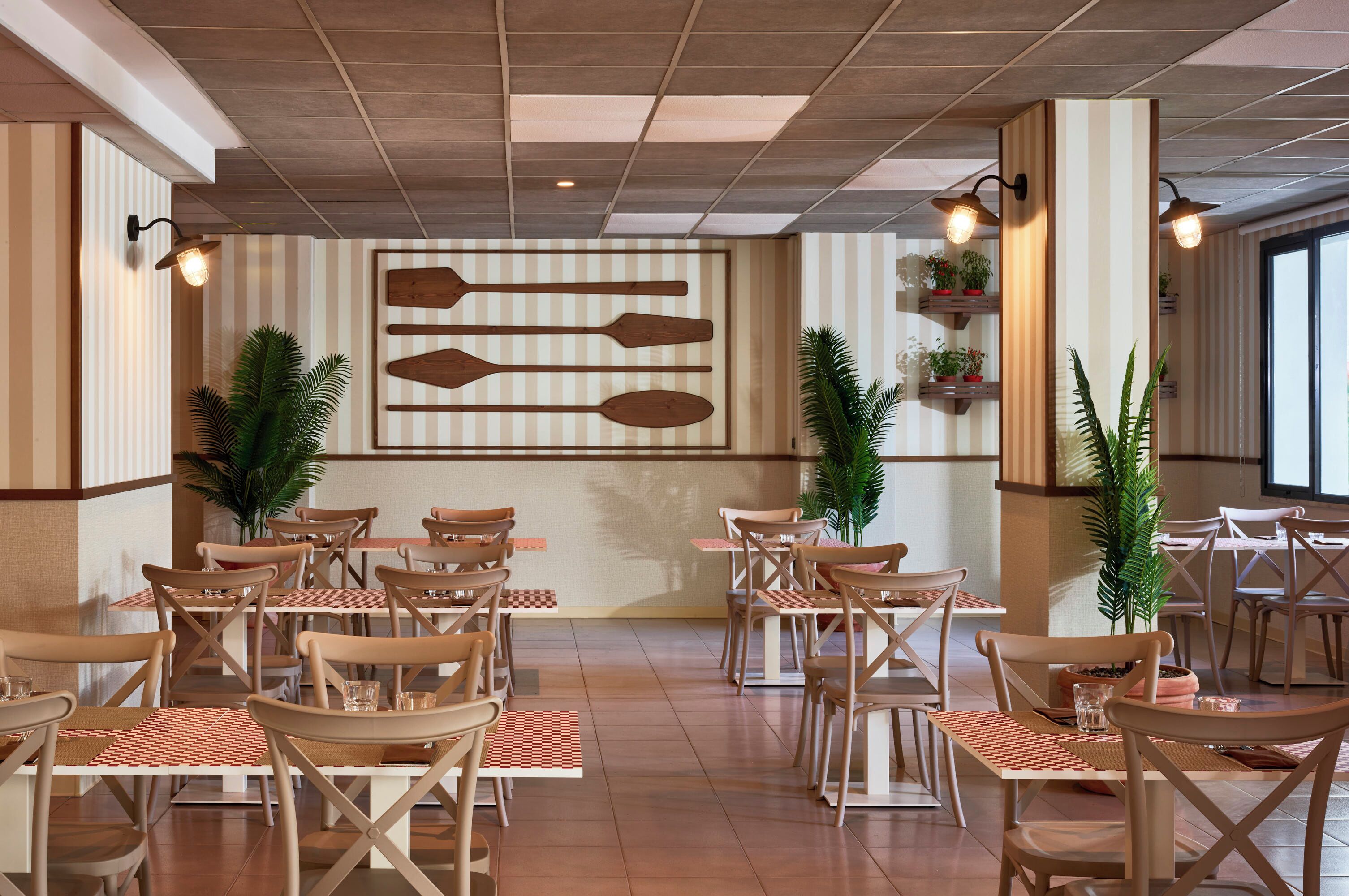 Un restaurant avec des chaises et des tables en bois, des murs à rayures et des plantes en pot.