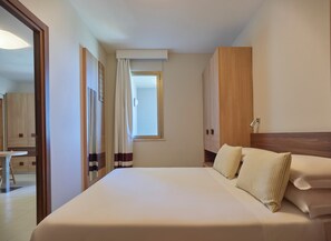 Une chambre d’hôtel avec un grand lit, une armoire en bois et une fenêtre avec des rideaux.