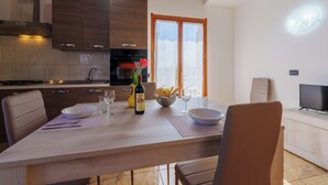 Une cuisine moderne avec des meubles de rangement en bois foncé, une table à manger dressée avec des assiettes, des verres et une bouteille.