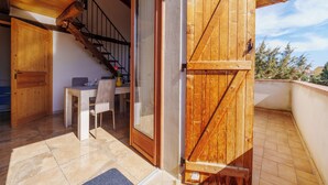 Un balcon en bois comprenant un espace repas, un escalier et une porte coulissante.