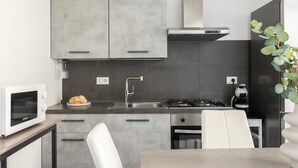 Una cocina moderna con armarios grises, un lavamanos de acero inoxidable, una estufa a gas y un microondas.