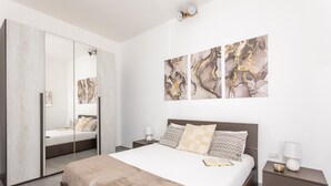Un dormitorio moderno con una cama grande, un armario, una mesita de noche y arte abstracto en la pared.