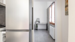 Una cocina moderna con un refrigerador empotrado, una pequeña mesa de comedor y un ventanal con vistas.