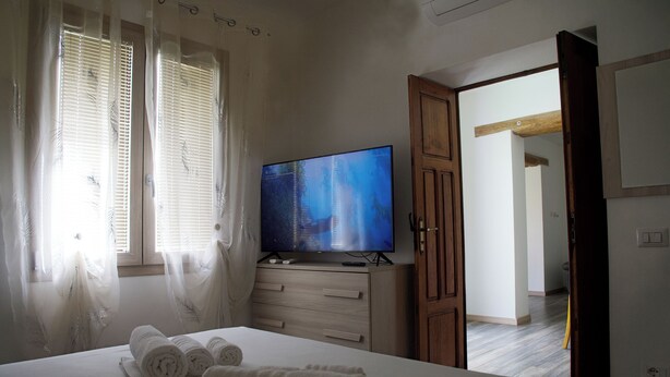 Een hotelkamer met een bed, een televisie en een houten garderobe.