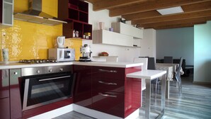 Een moderne keuken met een inbouwoven, een koffiezetapparaat en een magnetron. Er is een eethoek met een tafel en stoelen.