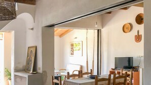 Uma área de refeições com mesa e cadeiras de madeira, uma televisão e um quadro na parede.