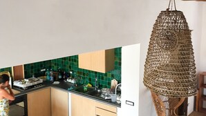 Cozinha com armários de madeira, painel de azulejos verdes e uma cesta de vime pendurada.