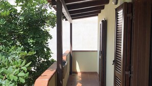 A narrow corridor with a tiled floor, wooden ceiling beams, and a wall-mounted planter.