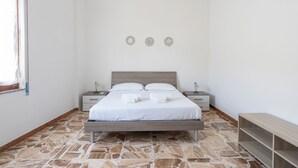 Un dormitorio con una cama, dos mesitas de noche, un banco y un suelo estampado.