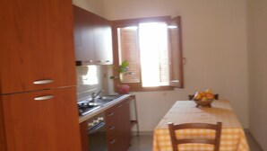Una cucina con mobili in legno, un fornello e un tavolo con tovaglia a quadri.
