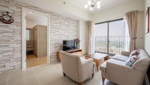 Ein Wohnzimmer mit einer Couch, Sesseln, einem Fernseher und einem Balkon mit Blick.