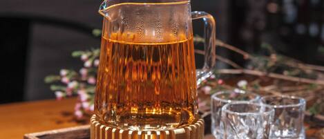 Una bandeja de madera con una taza de vidrio y cuatro vasos pequeños.