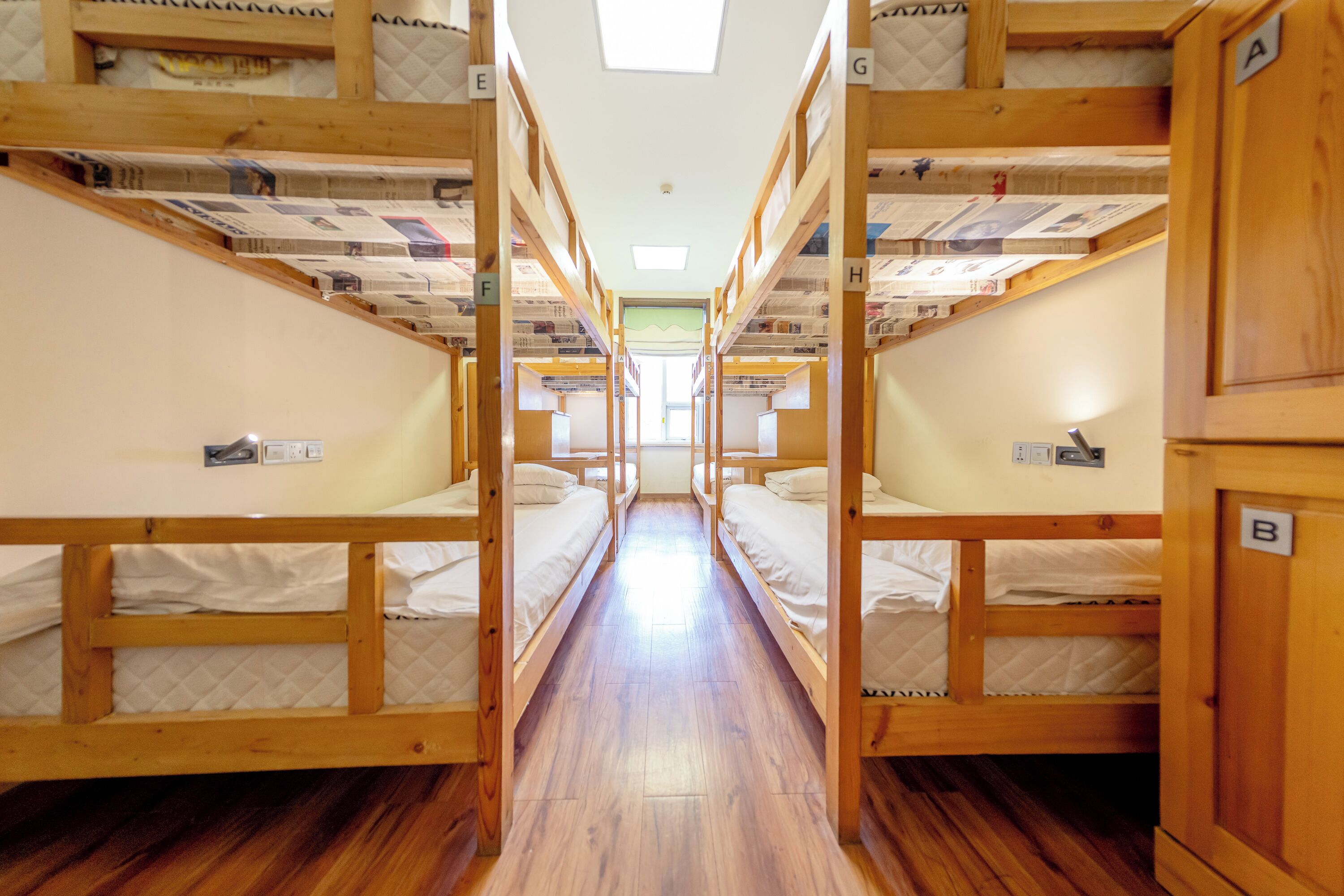 A corridor with bunk beds, wooden flooring, and a skylight.