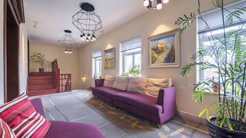 Ein modernes Wohnzimmer mit einem violetten Sofa, einer Treppe und Kunstwerken an den Wänden.