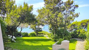 Un espace extérieur aménagé avec un sol en pierre, offrant une vue sur un jardin paysager et un plan d’eau.