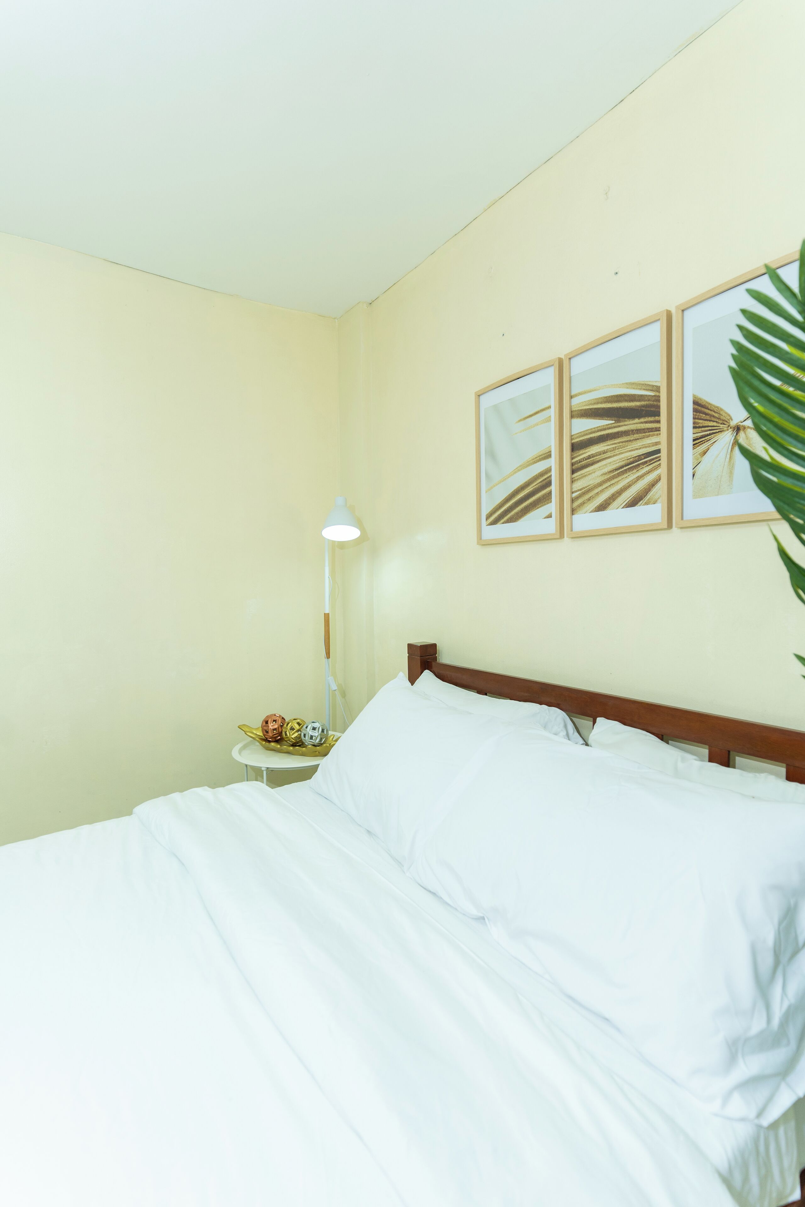 A neatly made bed with white linens, a bedside lamp, and a small table with decorative items.