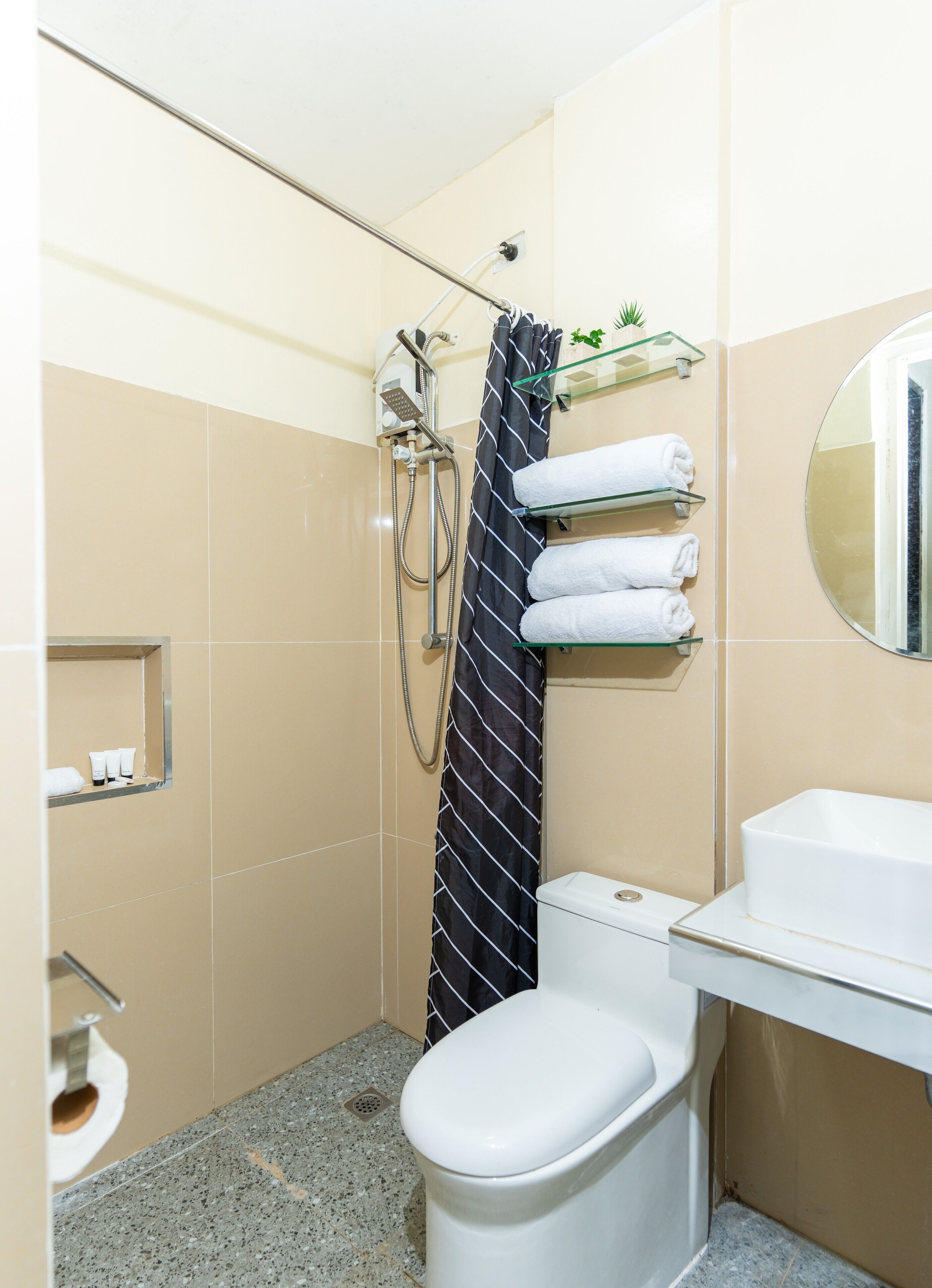 A small bathroom with a toilet, a shower, a sink, and a mirror.