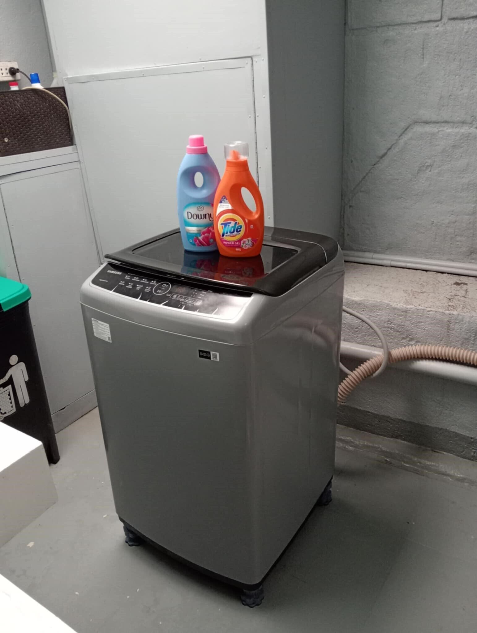 A compact, gray portable heater with a digital control panel, placed on a tiled floor next to a wall.