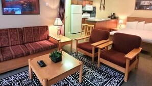 A compact hotel room with a sofa, two armchairs, a small table, a bed, a kitchenette, and a patterned rug. - Horsethief Ski In Out Studio / Fireplace / Hot tub (Panorama)