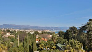 A coastal cityscape with a view of the sea and mountains in the distance.