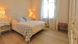 A bedroom with a bed, bedside lamps, a bench, and a wardrobe.
