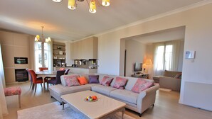 A modern living room with a sofa set, a coffee table, and a dining area with chairs and a table.
