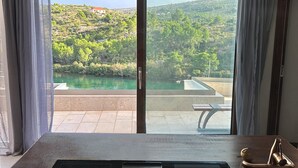 A kitchen with a built-in stove, a view of a green landscape, and a large window with curtains. - Oliven Penthouse (Sutivan)