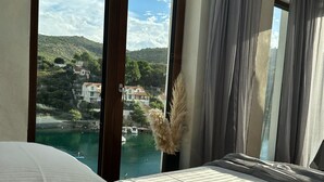 A hotel room with a bed, a view of a body of water, and a mountainous landscape. - Oliven Penthouse (Sutivan)