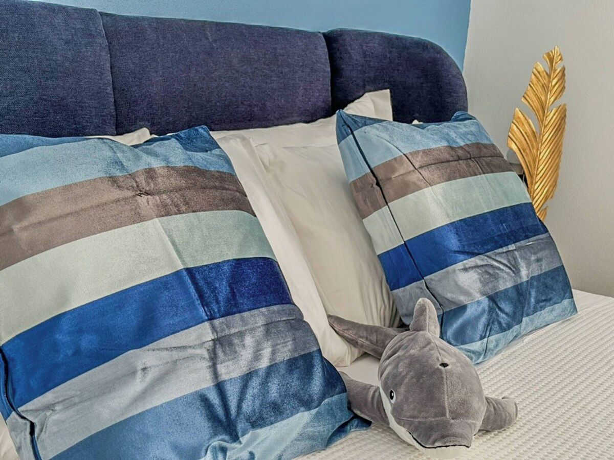 Un lit avec des oreillers à rayures et un animal en peluche.