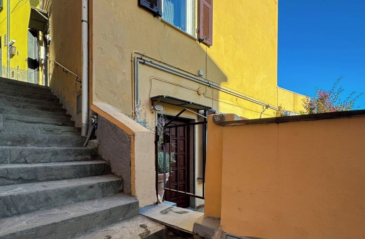 Un escalier menant à l’entrée d’un immeuble, avec une grille en métal et un petit auvent.