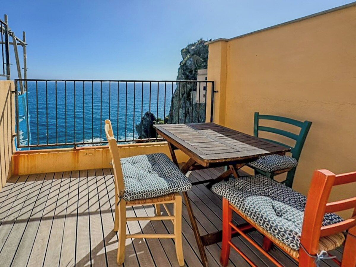 A deck with a table and chairs, overlooking a body of water.