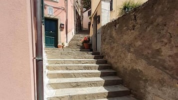A narrow stone staircase leading up to a building with a pink facade and a beige wall.