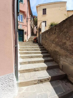 A narrow stone staircase leading up to a building with a pink facade and a beige wall. - Il Sogno di Beatrice Luxury Apartment (Manarola)