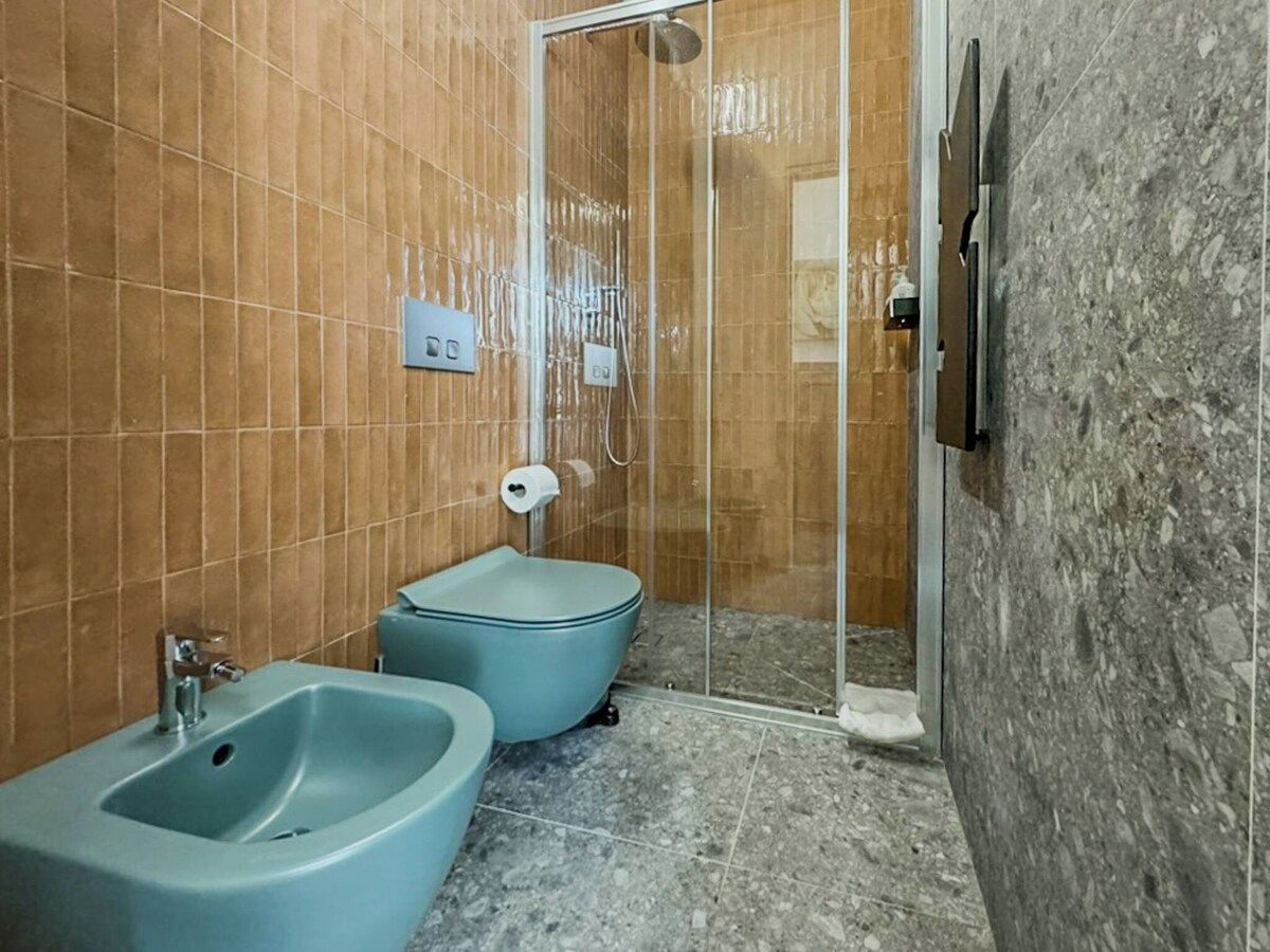 Ein Badezimmer mit integriertem Bidet, Toilette und Duschkabine.