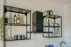 A kitchen with black shelving units, a built-in stove, and a hanging plant.