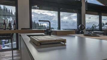 A modern kitchen with a large window overlooking a snowy mountain landscape.