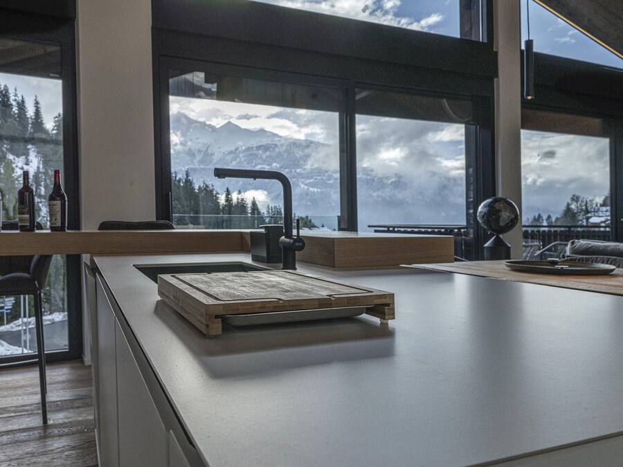 A modern kitchen with a large window overlooking a snowy mountain landscape.