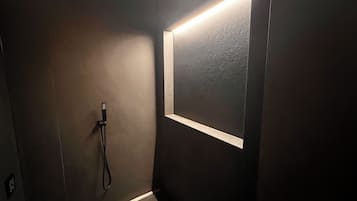 Une salle de bain moderne avec un mur de couleur sombre, une douche intégrée et une petite fenêtre agrémentée d’un bandeau lumineux.