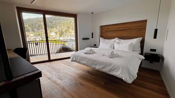 Un dormitorio moderno con cabecera de madera, una cama grande con ropa de cama blanca, una mesita de noche y un escritorio.