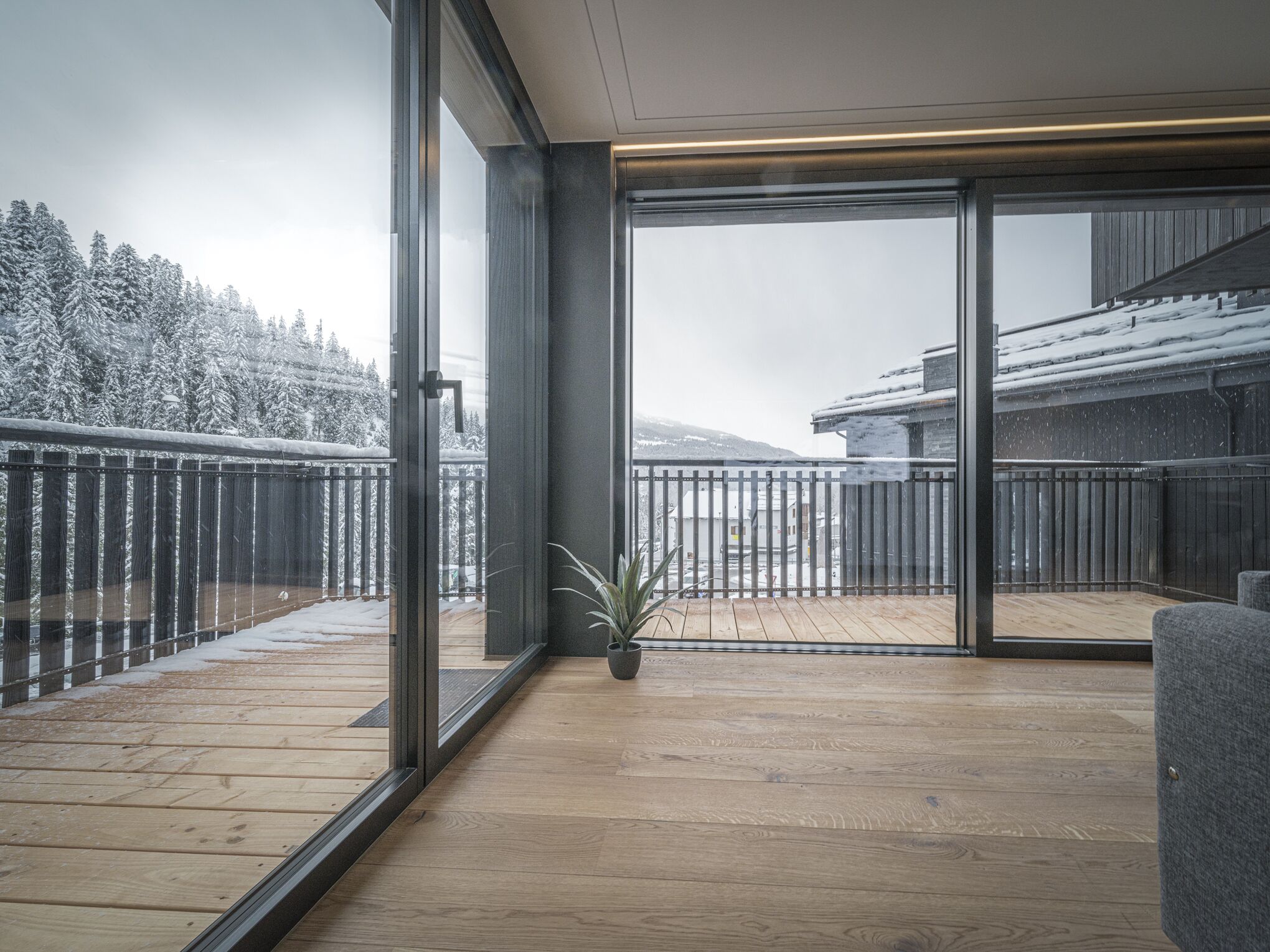 Un interior moderno con grandes puertas de vidrio que dan a una terraza de madera.
