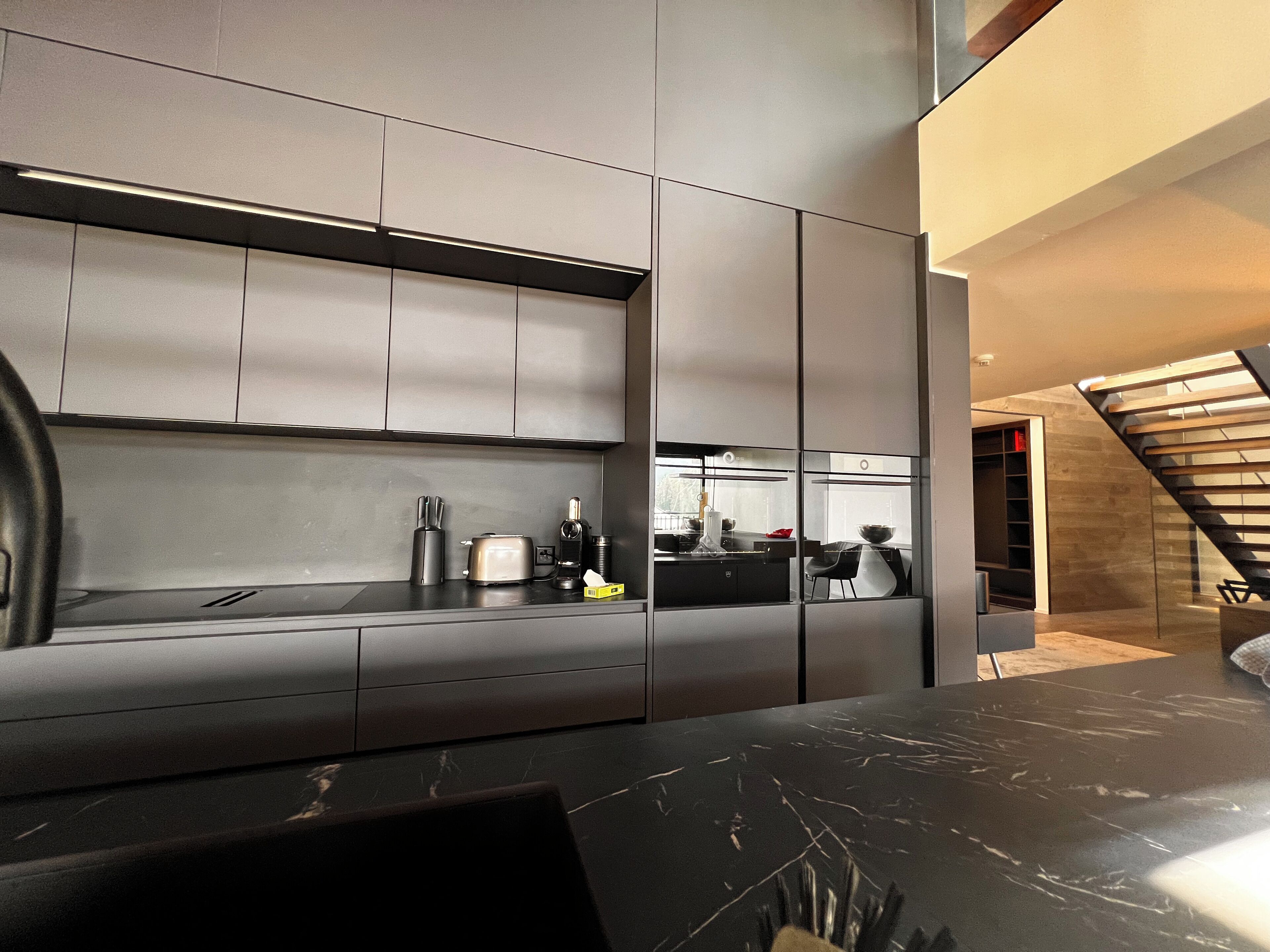 Una cocina moderna con armarios elegantes, encimera negra y estufa a la vista.