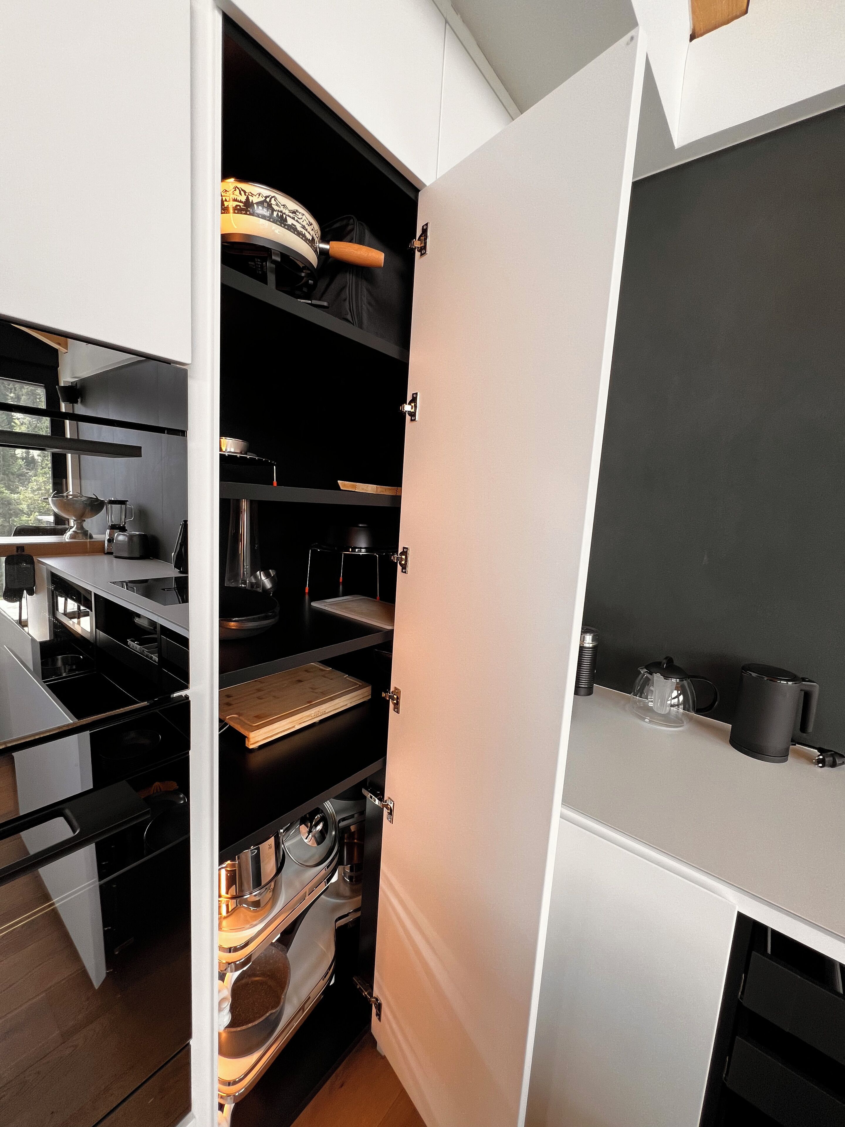 Una cocina con armarios abiertos que muestran electrodomésticos y utensilios.