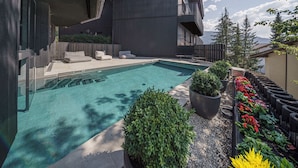 Un edificio moderno con piscina, asientos al aire libre y un jardín con flores.