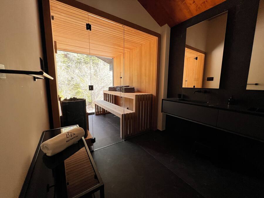 Un baño moderno con un espejo grande, paneles de madera y un banco.