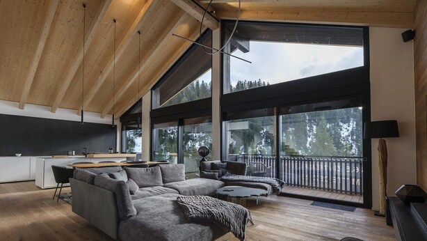 Una sala de estar moderna con un sofá modular, un comedor y ventanas amplias con vistas al exterior.