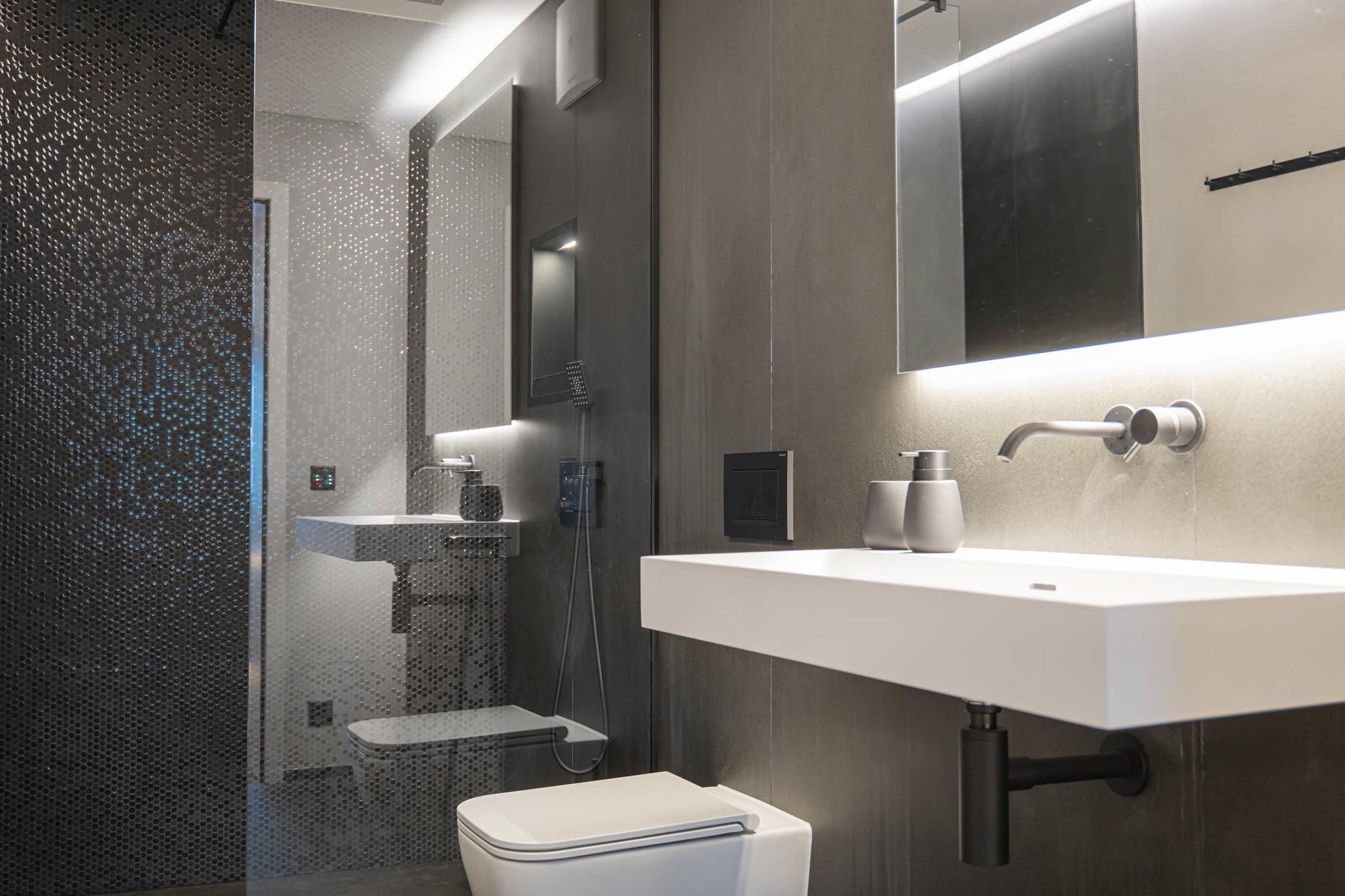 A modern bathroom with a shower, toilet, and sink.