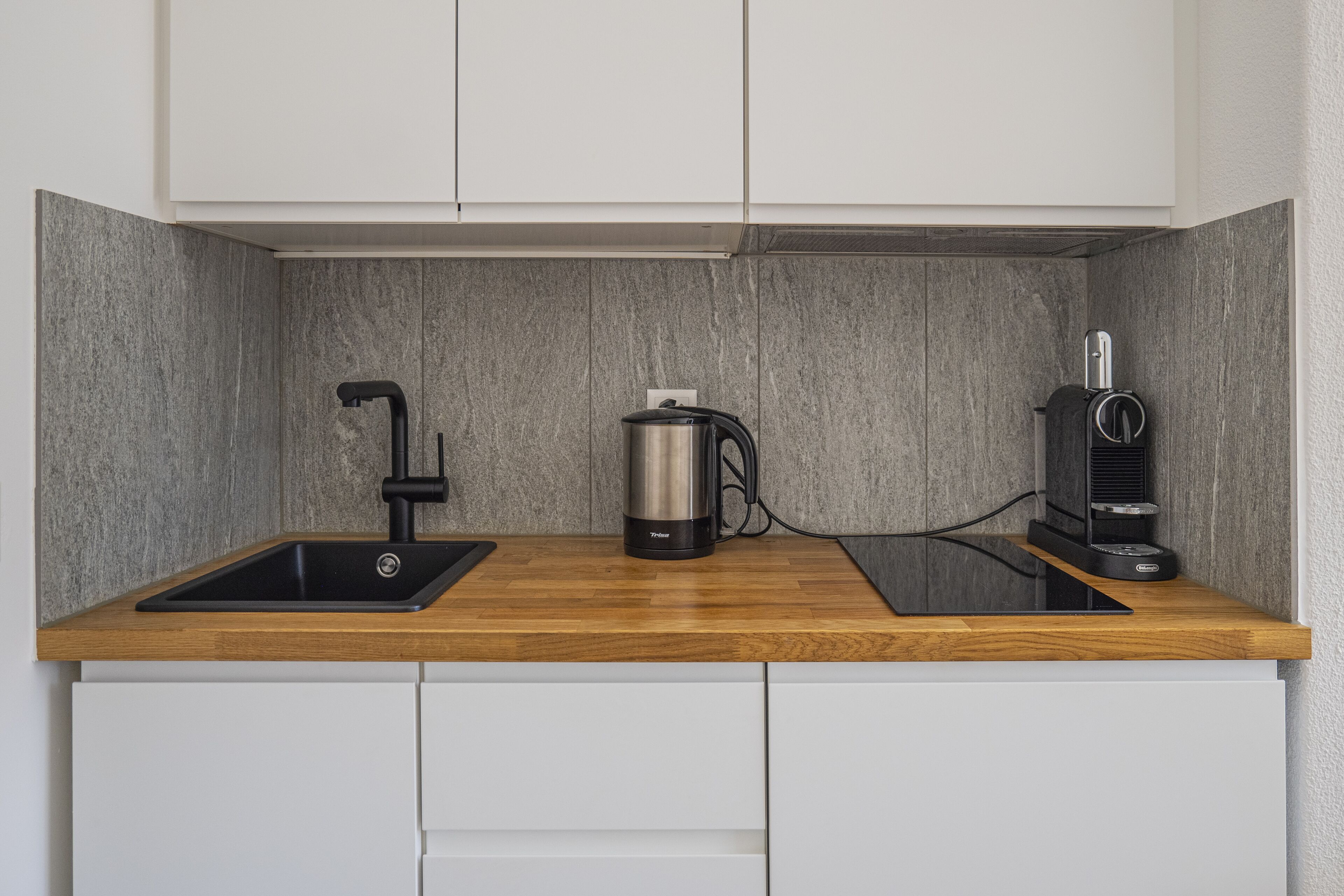 Una cocina con encimera de madera, un fregadero, una tetera y una cafetera.