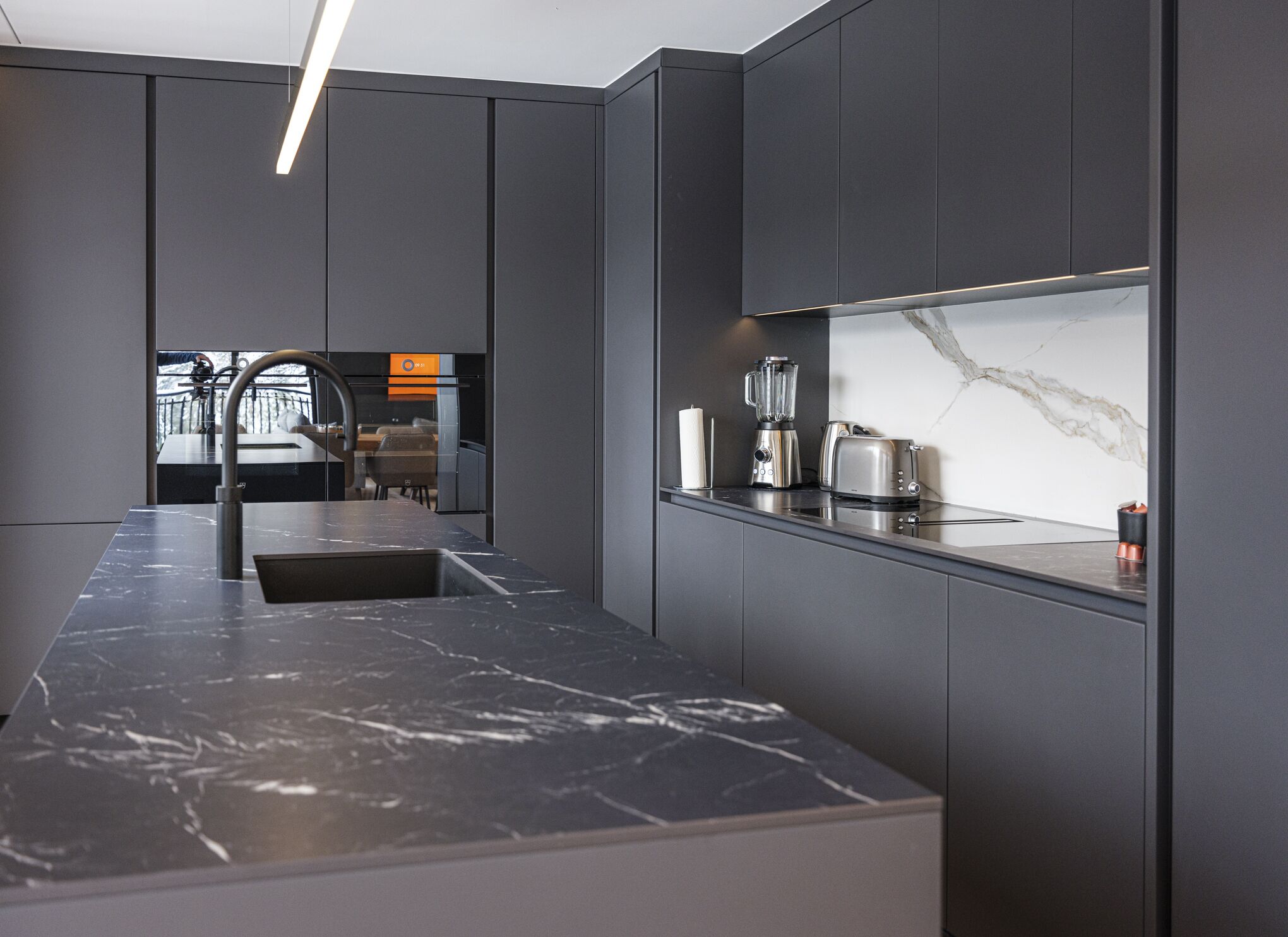 Una cucina moderna con un piano di lavoro in marmo, un lavello incassato e una macchina da caffè.