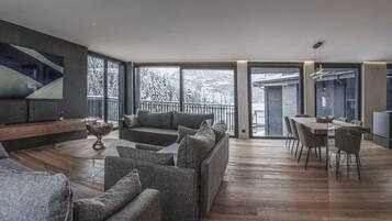 A modern living room with a sofa, a coffee table, and a dining area with a table and chairs.
